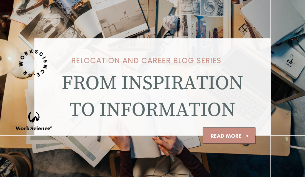 The image is an overhead view of a busy, creative desk space. The desk is cluttered with magazines, photos, a laptop, papers, and design materials. A person is seated at the desk, writing in a notebook.